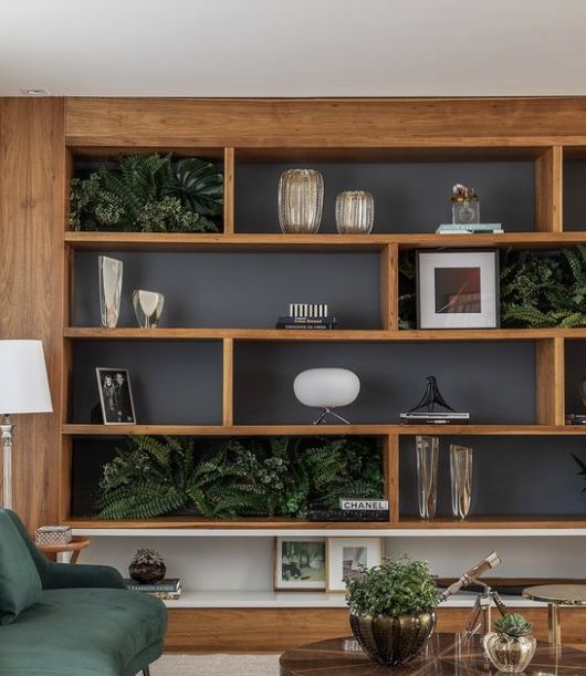 a living room filled with lots of furniture and plants on top of wooden bookshelves