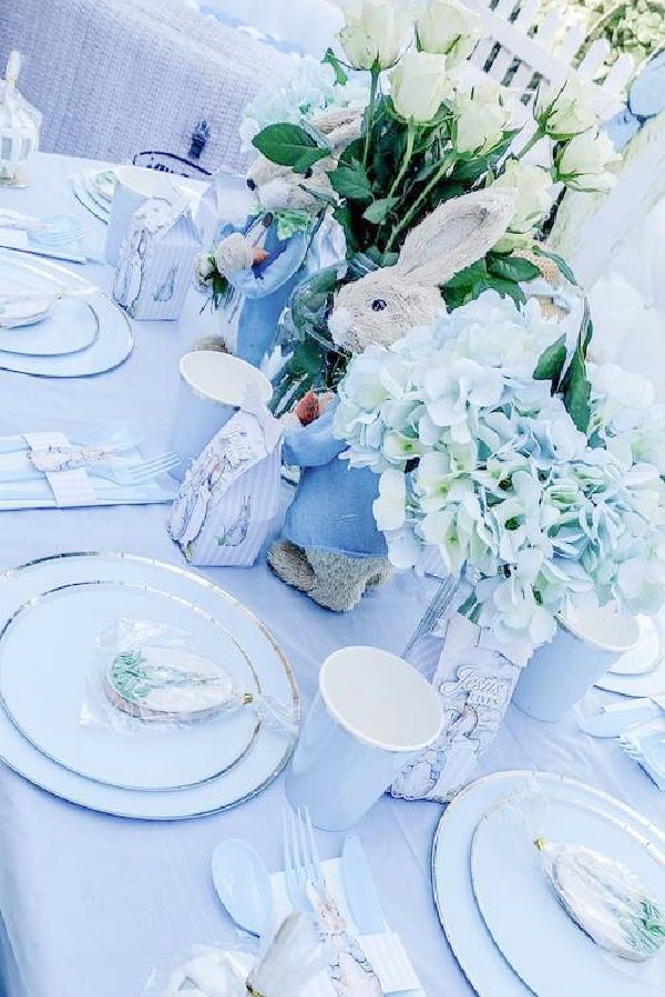 the table is set with blue and white plates, silverware, and flowers in vases