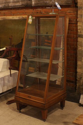 a wooden display case sitting next to a white couch in a room with brick walls