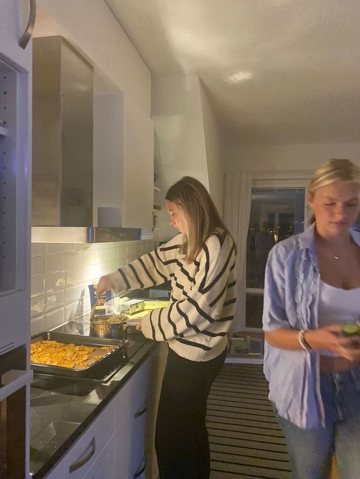 two women standing in a kitchen preparing food