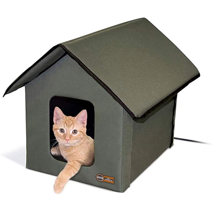 an orange cat laying inside of a green house with its paw in it's mouth