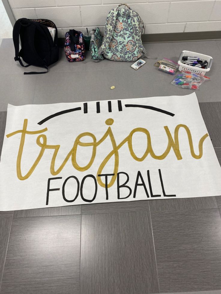 a sign on the floor that says tropon football next to other school supplies