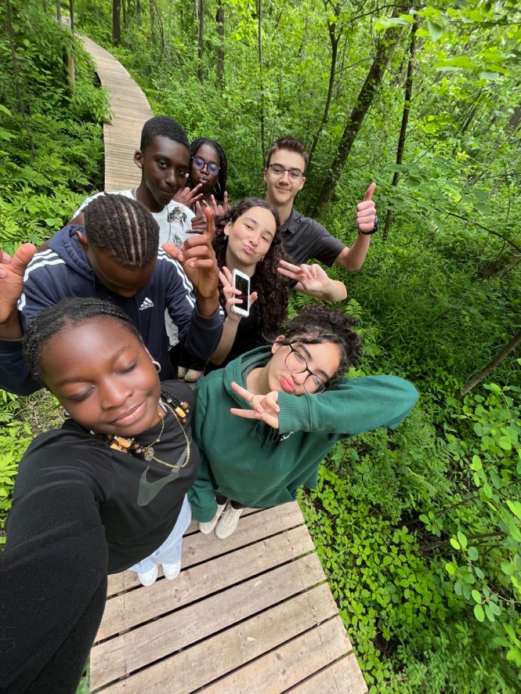 a group of people standing on top of a wooden walkway in the woods posing for a photo