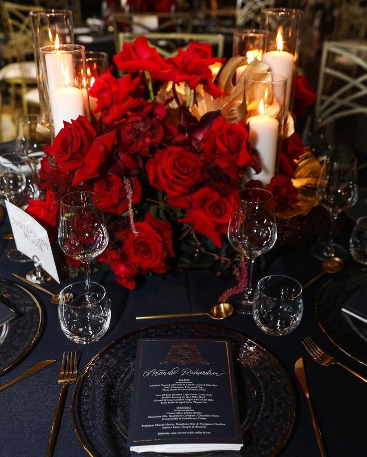 the table is set with red roses, candles and menu cards for dinner guests to enjoy