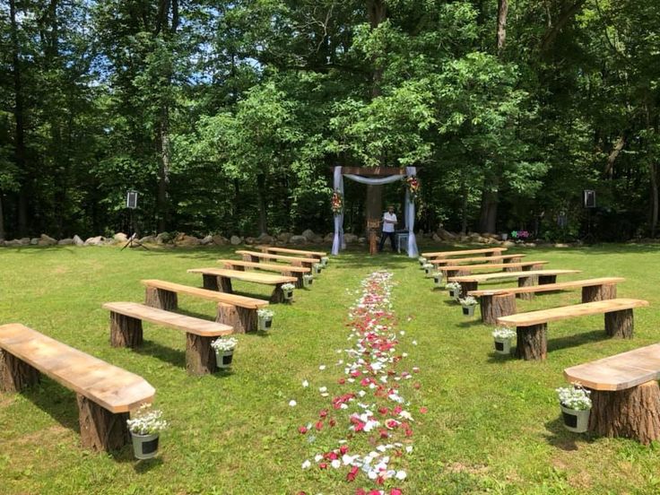 an outdoor ceremony setup with wooden benches and flowers