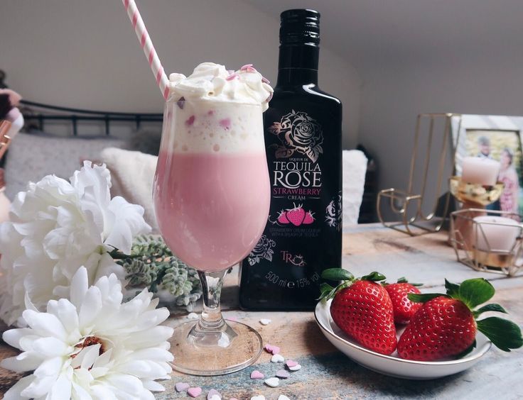 a strawberry milkshake with whipped cream and strawberries on the table next to it