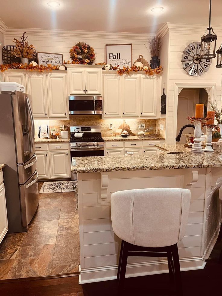 a kitchen with white cabinets and marble counter tops, an island in the middle is surrounded by two stools