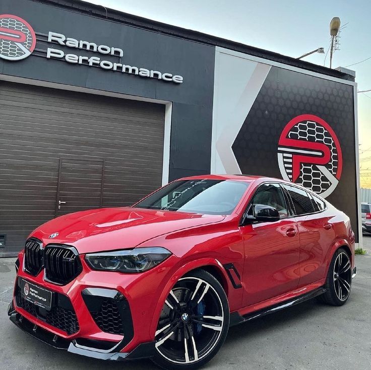 a red bmw x4 parked in front of a building with the logo on it