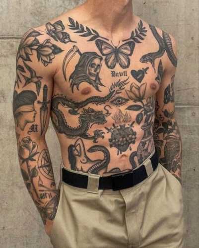 a man with many tattoos on his chest and arms is standing in front of a wall