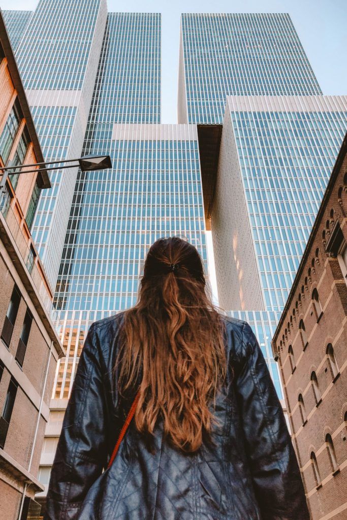 a man with long hair walking down the street in front of tall buildings and skyscrapers