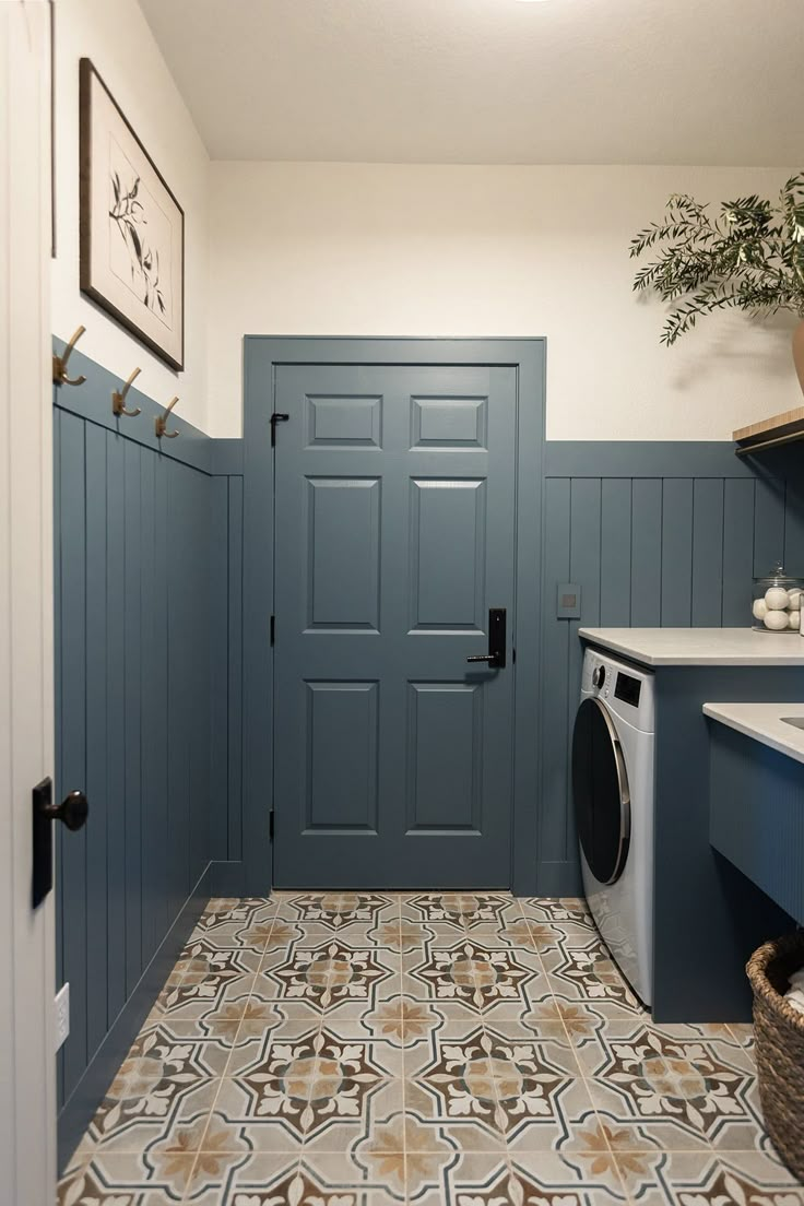 a washer and dryer in a laundry room with blue walls, patterned flooring and wooden cabinets