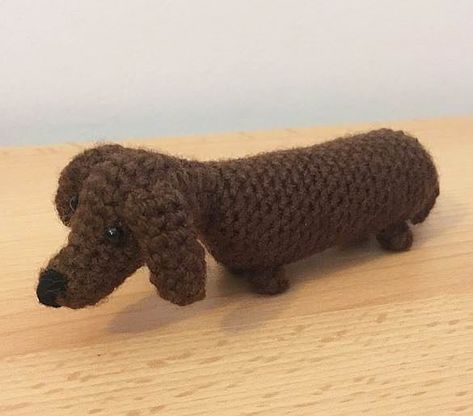 a crocheted dog is standing on a wooden surface