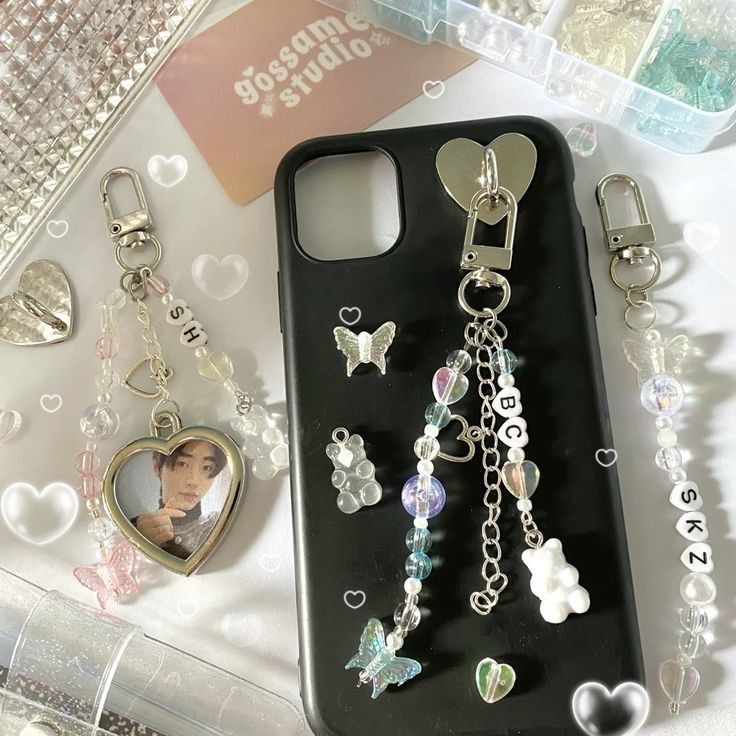 a cell phone case with charms on it and a heart shaped keychain attached to the back