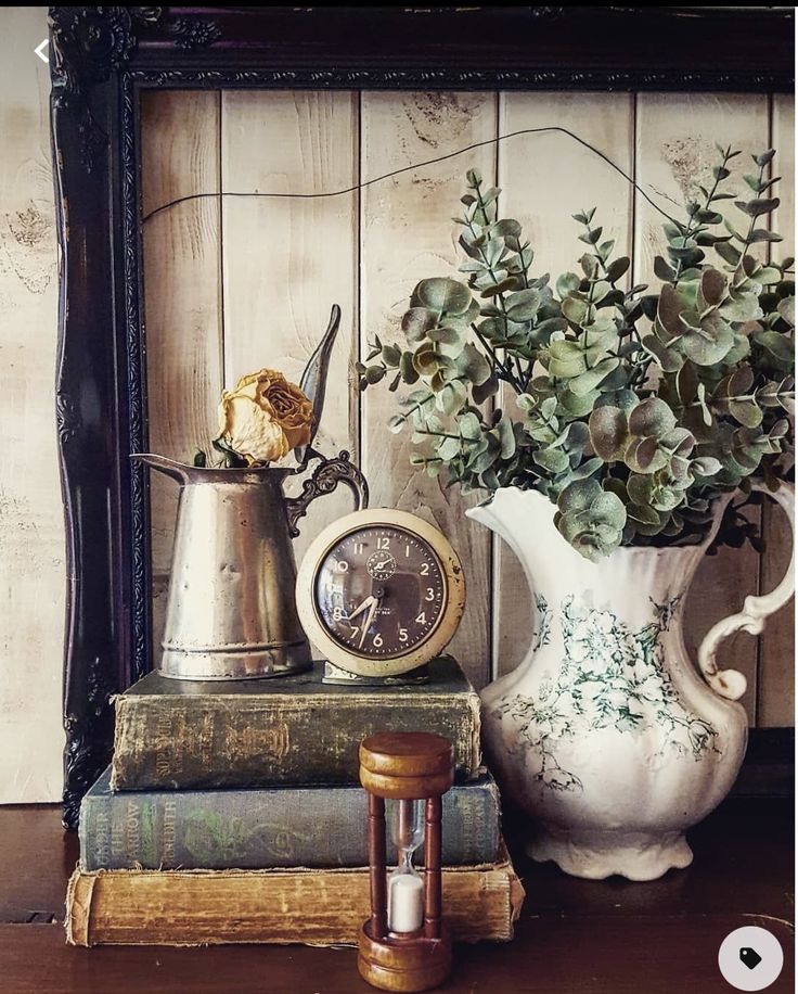 there is a vase with flowers on top of books and an alarm clock next to it