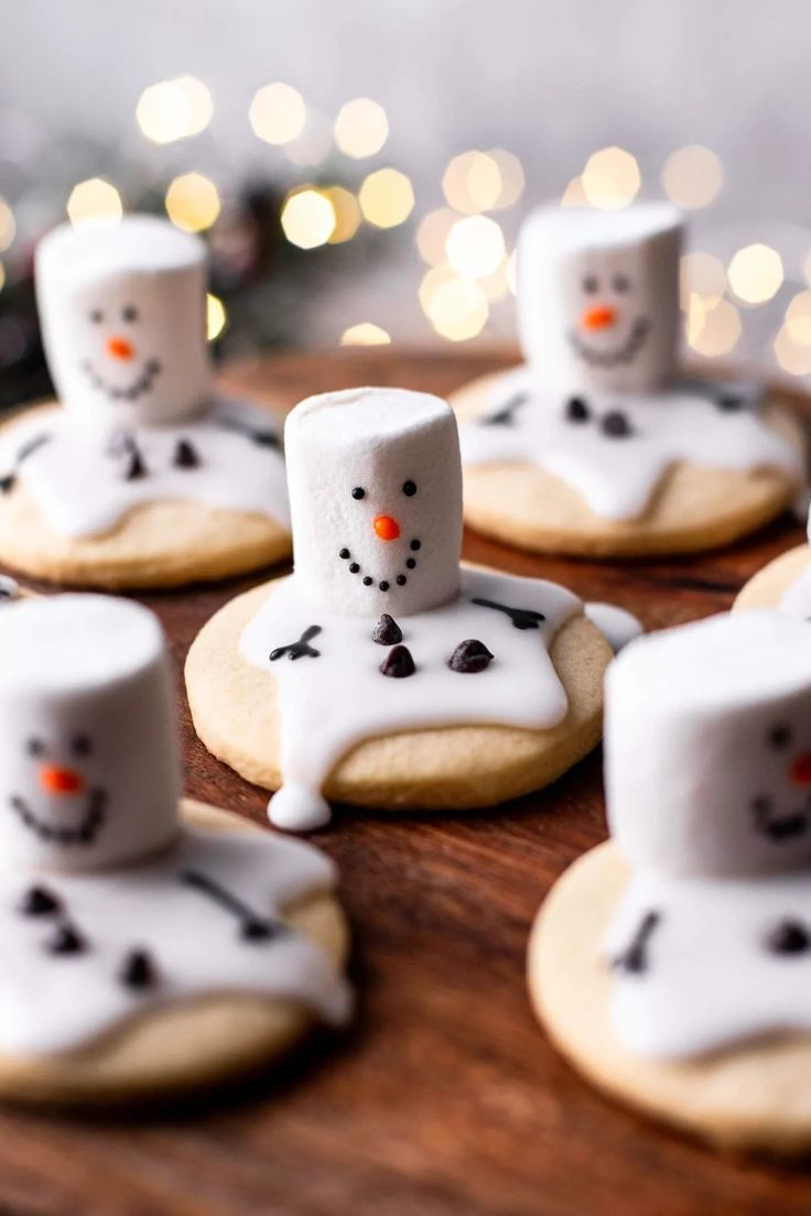 decorated cookies with marshmallows in the shape of snowmen on a wooden table