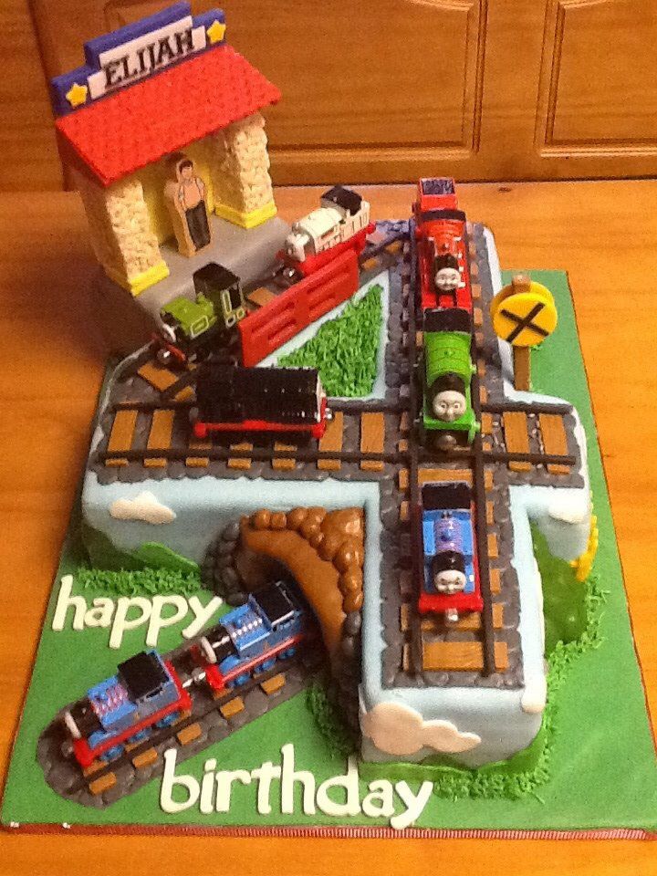 a birthday cake that is shaped like a train track with a building and cars on it