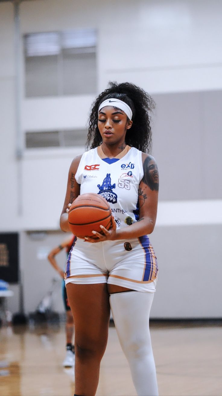 a woman holding a basketball on top of a court