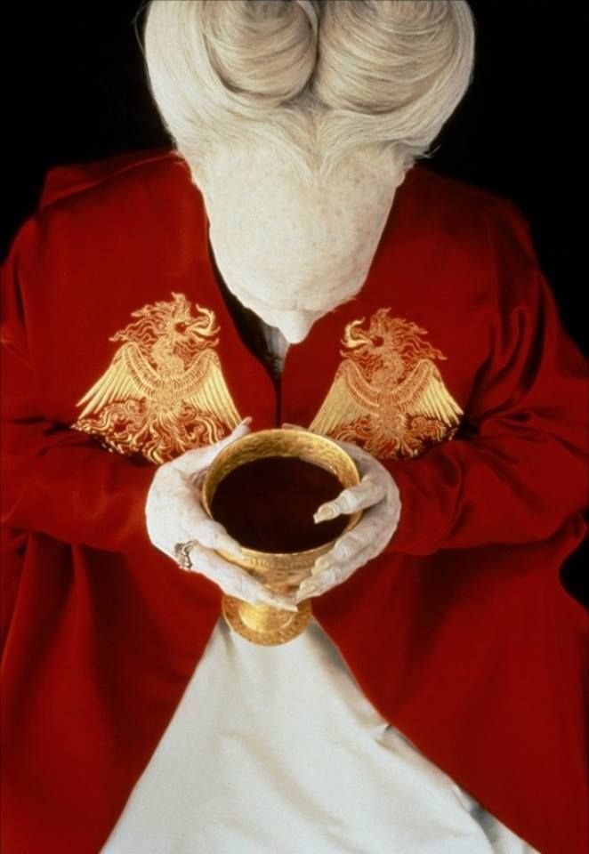 an old man dressed in red and white holding a cup