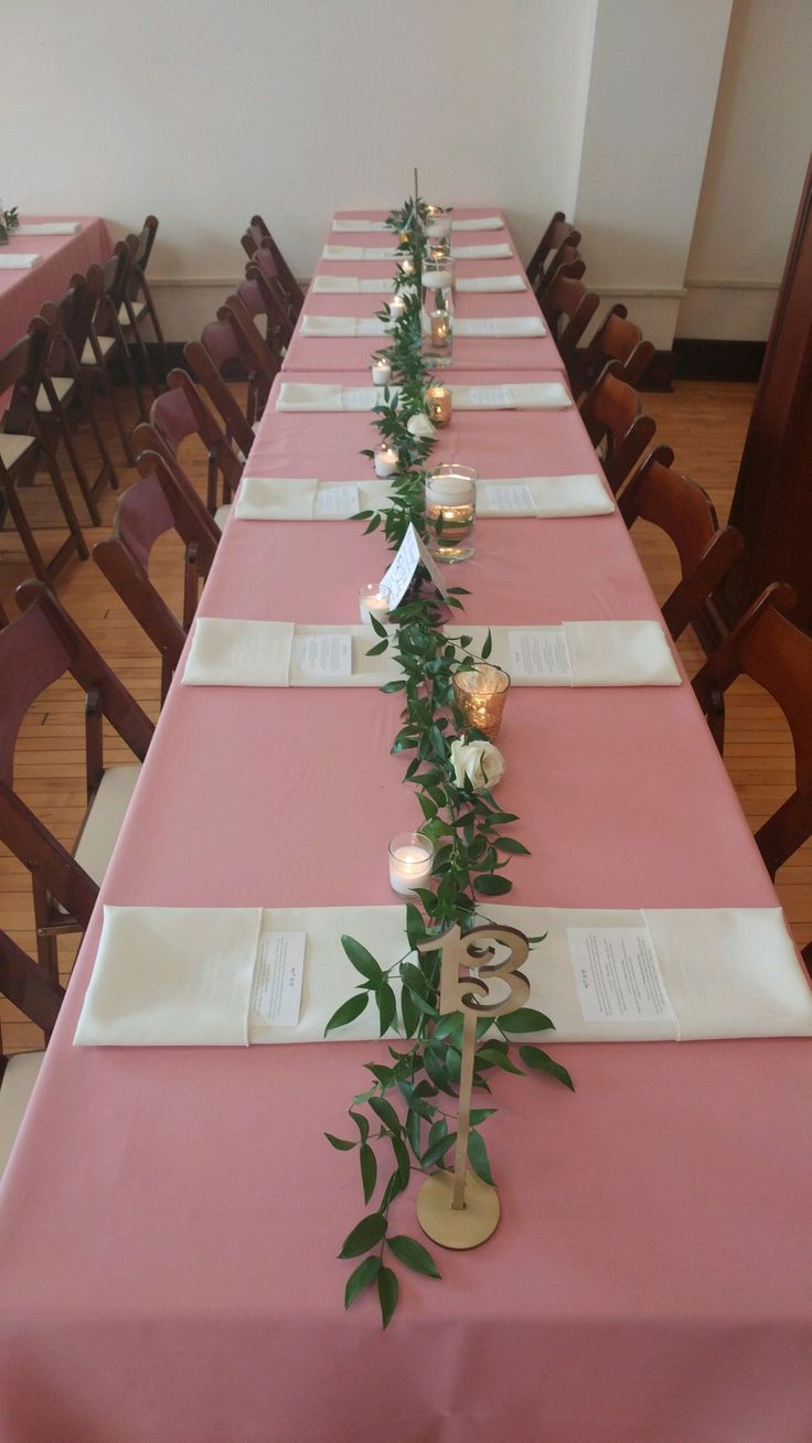 the long table is set with pink linens and place settings for guests to sit at