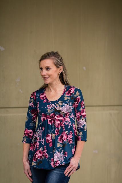 a woman standing in front of a wall with her hands on her hips and looking at the camera