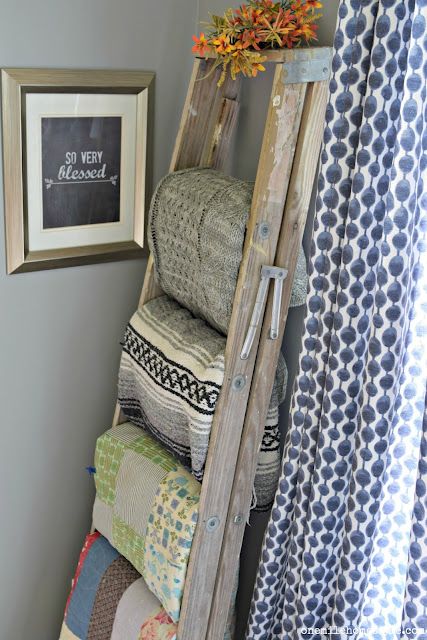 an old ladder is used as a shelf for blankets