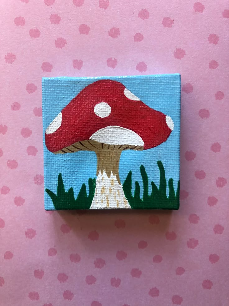 a small painting of a mushroom on a pink background with polka dots and green grass