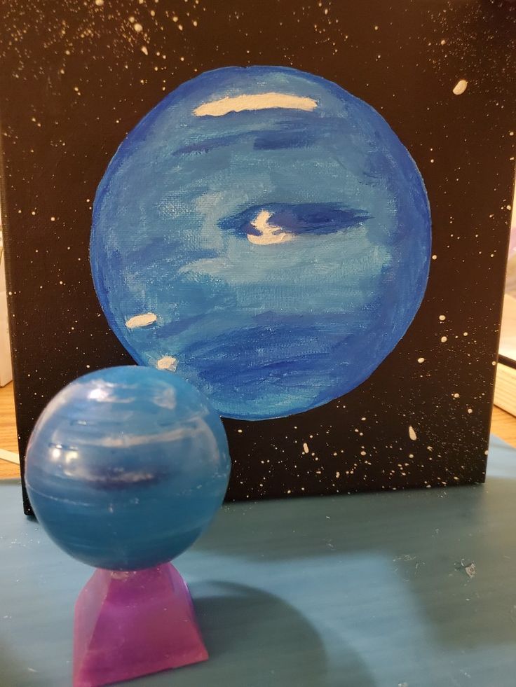 a blue ball sitting on top of a pink stand next to a black and white painting