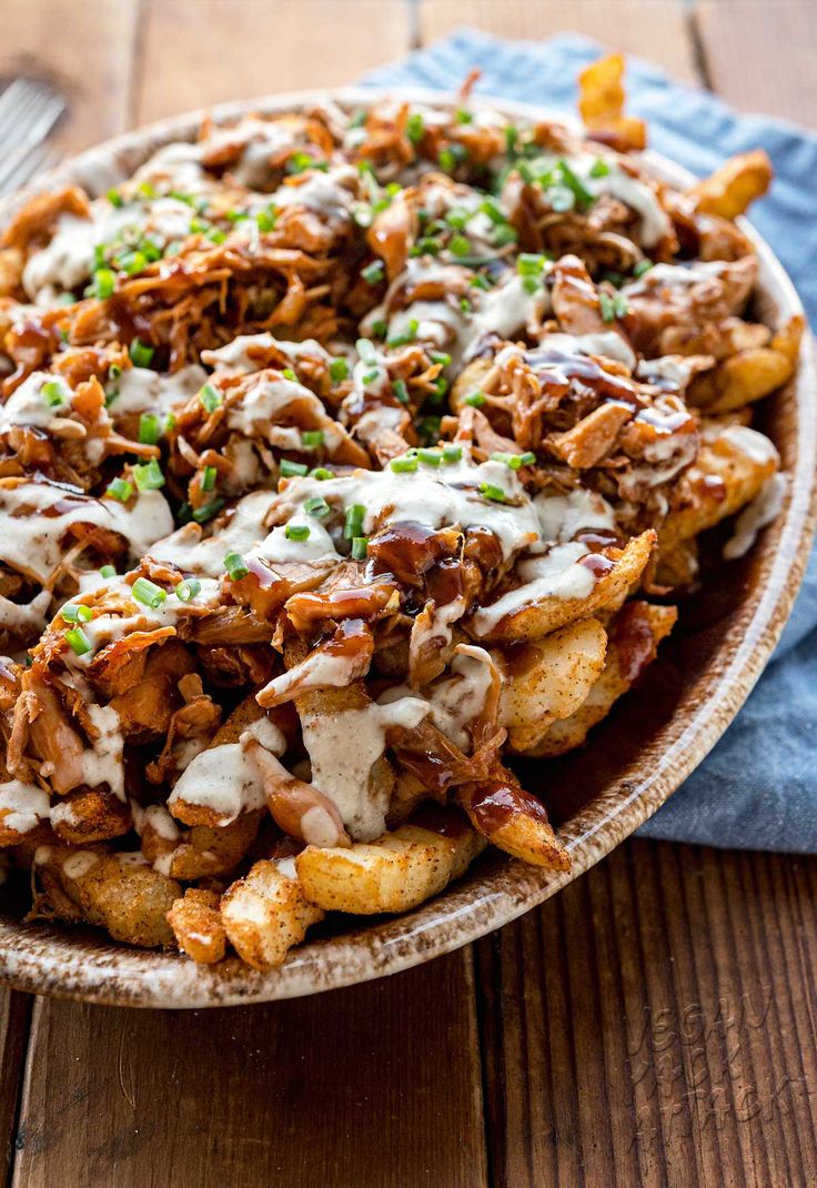 a large bowl filled with fried food on top of a wooden table next to a fork