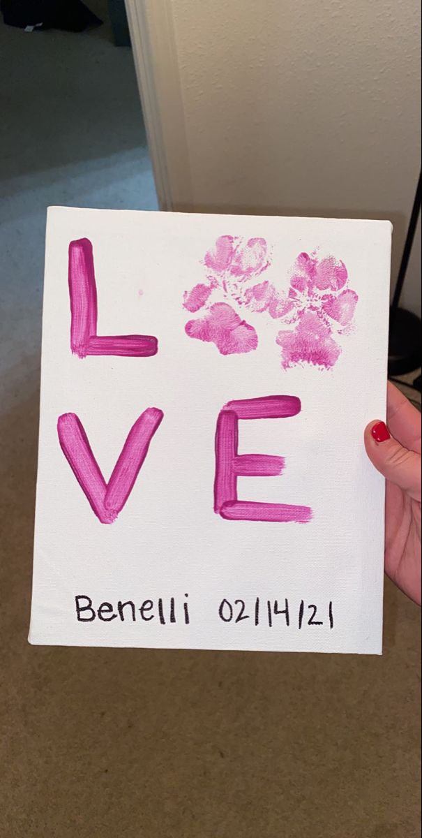 someone is holding up a card with the word love painted on it and pink flowers