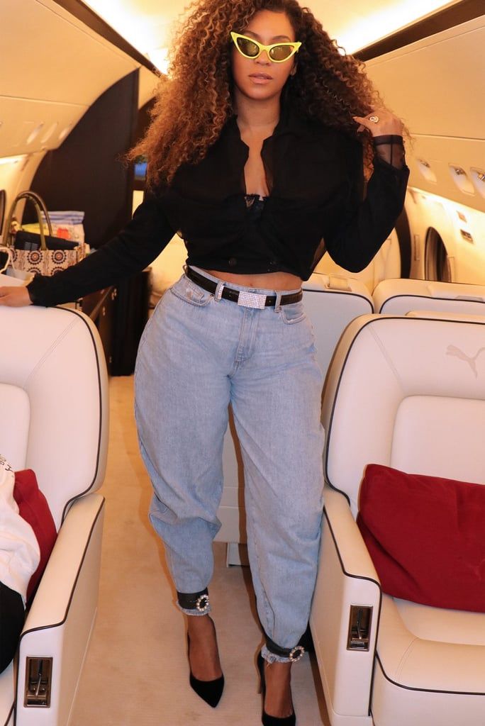 a woman standing in the back of an airplane with her hands on her hips and wearing sunglasses