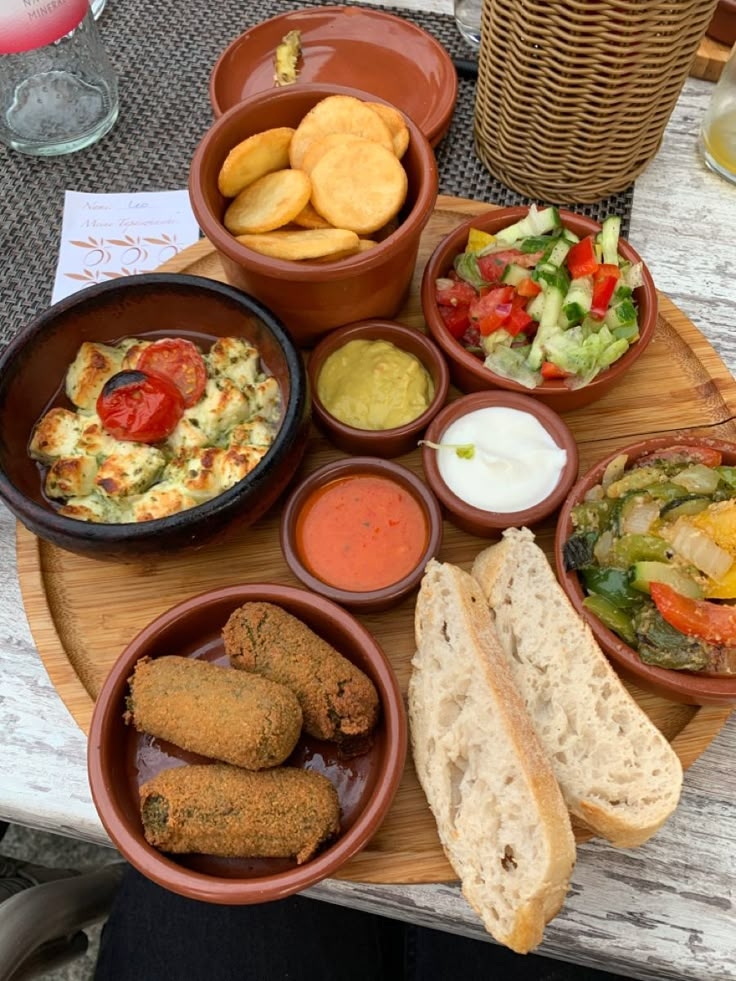 a wooden table topped with bowls filled with different types of food and dipping sauces