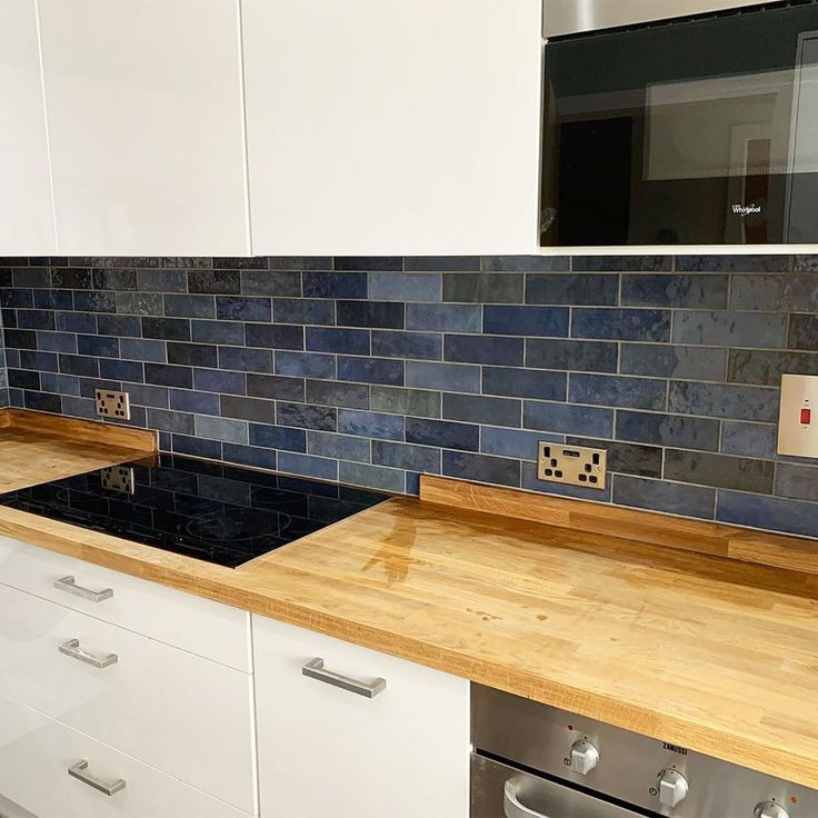 a kitchen with white cabinets and blue tile backsplashes on the counter tops