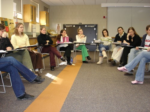 a group of people sitting around each other in front of a class room full of students