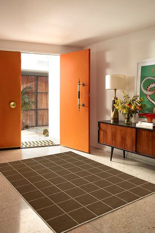 a living room with an orange door and rug on the floor