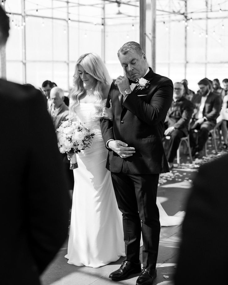 a man and woman standing next to each other in front of a group of people