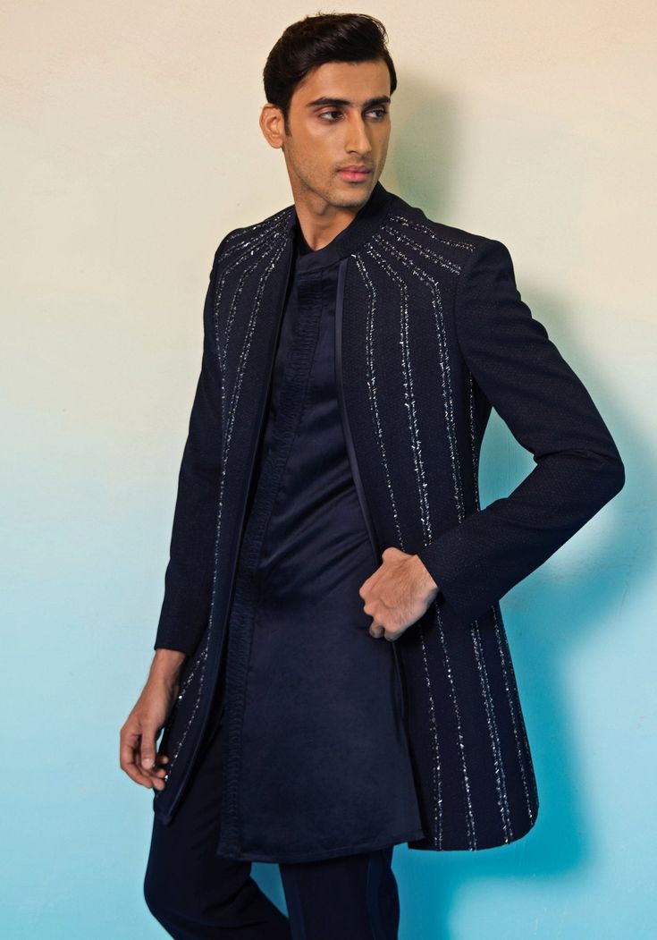 Elevate your style at any special occasion with our Navy Blue Open Jacket Sherwani Set. This stunning ensemble features a textured open jacket adorned with sparkling crystals and metallic elements, exuding sophistication and charm. Paired with a kurta and pants, this outfit is perfect for glamorous evening events like cocktail parties, sangeets, or wedding receptions. Make a lasting impression as the groom or a member of the groom's family. Stand out in this timeless and elegant sherwani set. Composition : Jacket, Kurta & Pants: Textured Suiting Care: Dry Clean Only and Vacuum Storage This product can be customized for sleeves, length of blouse and neckline Delivery : 4-6 weeks as the product is hand crafted. Check Size Guide or choose MySize for free customisation (All Sizes above XL can Designer Embellished Kurta For Eid, Designer Embellished Kurta For Festive Occasions, Designer Embellished Festive Kurta, Elegant Traditional Drape Outerwear For Party, Elegant Party Outerwear With Traditional Drape, Hand Embellished Long Sleeve Kurta For Reception, Embellished Bandhgala For Eid, Designer Long Sleeve Nehru Jacket With Mirror Work, Embellished Sherwani For Eid Party