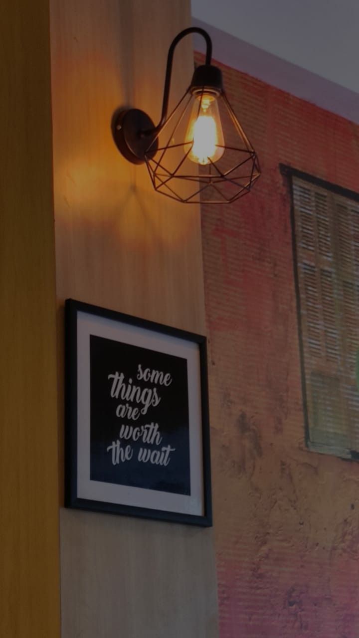 a light hanging from the side of a wall next to a framed poster on a brick wall