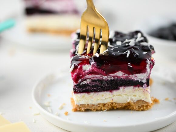 a piece of cake on a plate with a fork stuck in it and blueberries