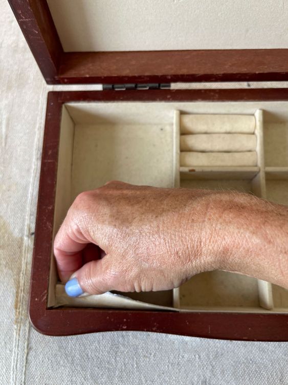 an old man's hand holding a mouse in a wooden box