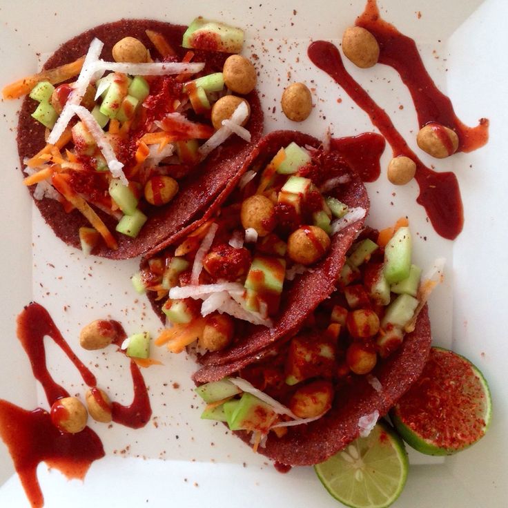 some tacos are sitting on a plate with sauce and garnishes around them