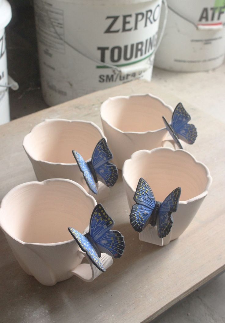 four cups with blue butterflies on them sitting on a table