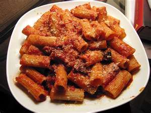 a white plate topped with pasta and meat covered in sauce on top of a table