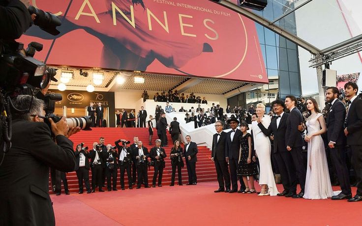 a group of people standing on top of a red carpet next to each other in front of a crowd