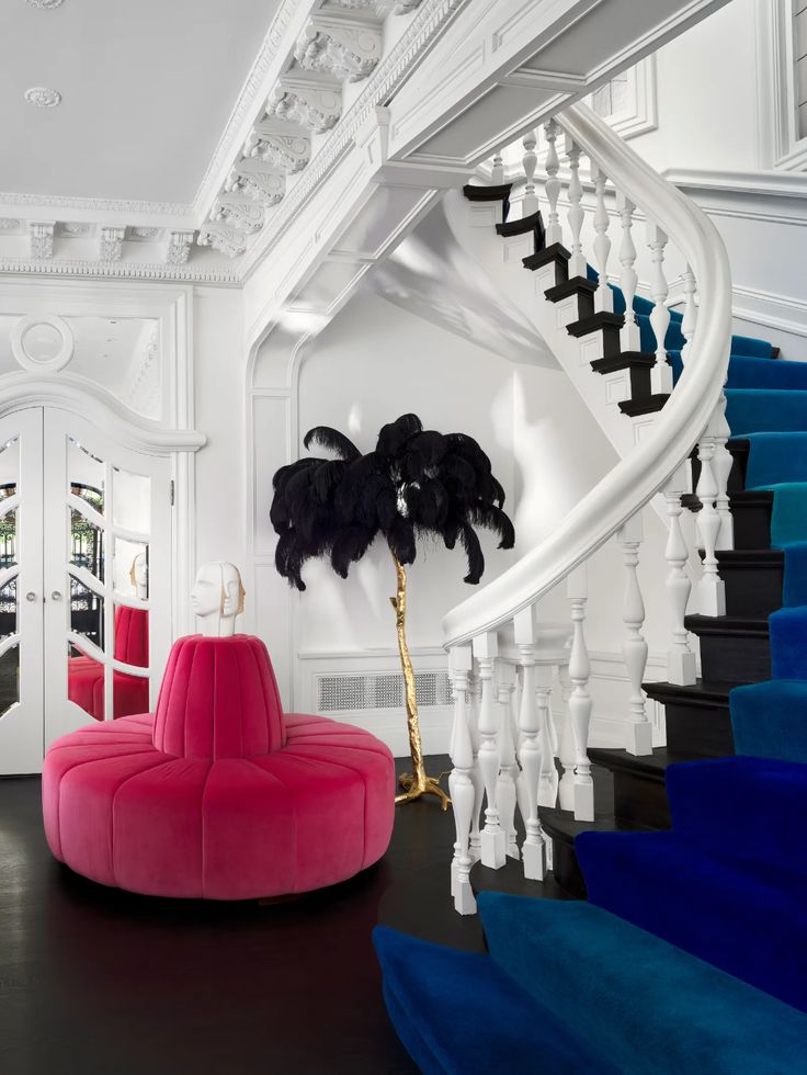 a red chair sitting in front of a stair case next to a blue and white staircase