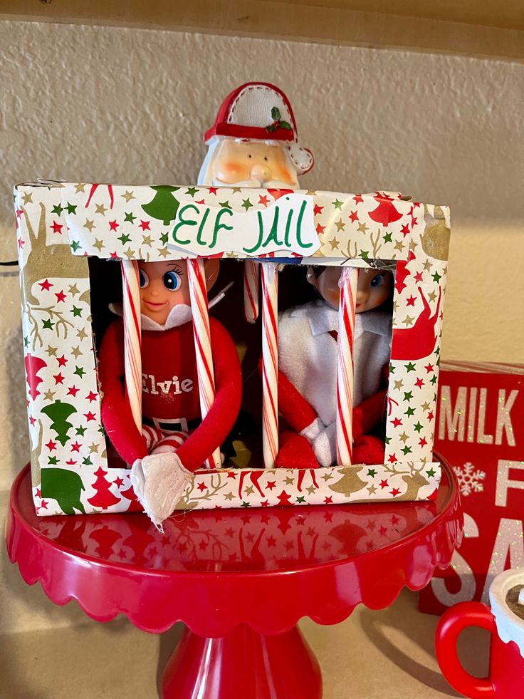 two elf dolls in a christmas frame on a table