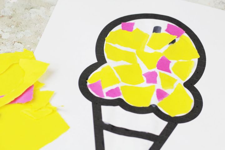 an ice cream cone cut out on paper next to yellow and pink pieces of construction paper