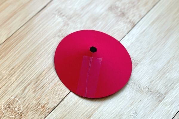 a piece of pink paper with a hole in the middle on a wooden table top