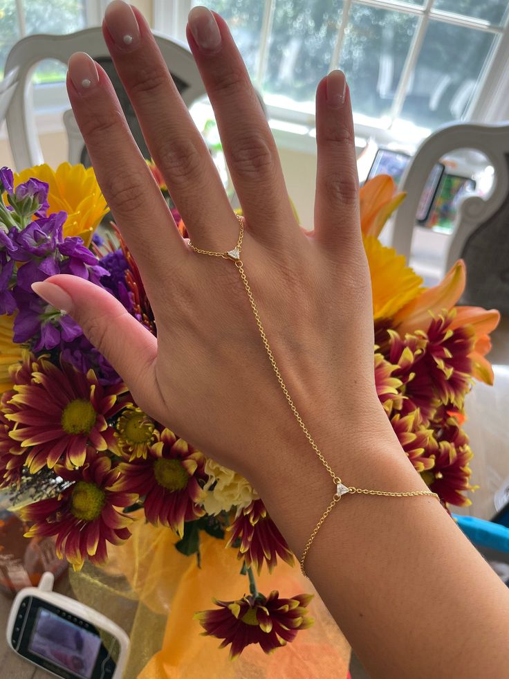 ✨ Perfectly dainty hand chain featuring 2 crystal triangle prism pendants and dainty thin gold chain. This fits perfectly on your middle finger and attaches as a bracelet.  ✨ Please choose your ring size! ✨ Bracelet measures about 6.5 inches (and will be proportionate to your ring size). ✨ Free shipping in the U.S!  You can see other hand chains here:  https://www.etsy.com/shop/houseofgilt/?section_id=17203243 Follow and tag me on Instagram and TikTok @houseofgilt @houseofgilt @houseofgilt Hand Bracelet With Ring, Gold Hand Chain, Hand Chain Jewelry, Finger Bracelets, Gold Jhumka Earrings, Neck Pieces Jewelry, Hand Chain Bracelet, Ring Bracelet Chain, Crystal Pendants