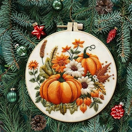 an embroidered ornament with pumpkins and daisies on it, surrounded by pine cones