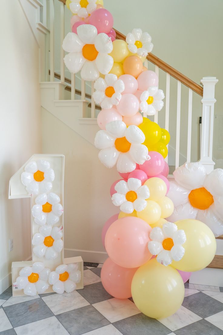 some balloons and flowers are on the floor in front of a stair case at a party